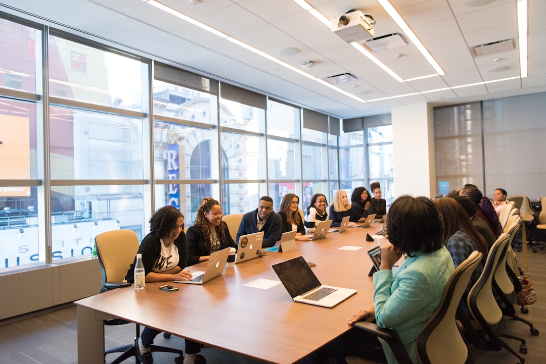 people sitting on chair in front of table while holding pens during daytime