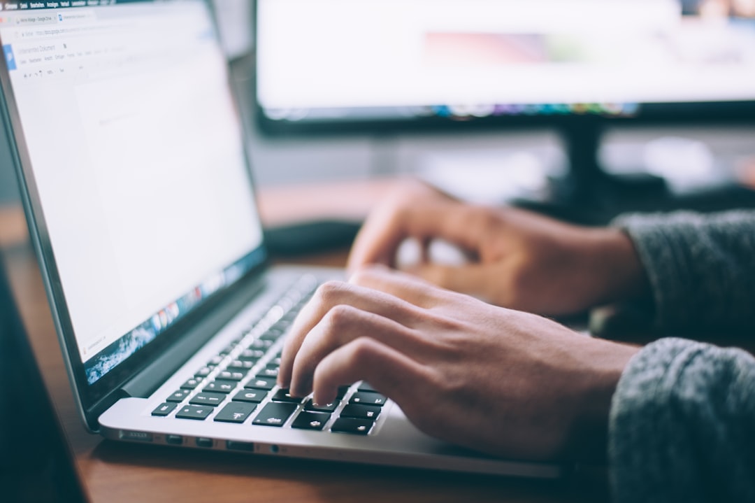 man in gray sweatshirt sitting on chair in front of iMac