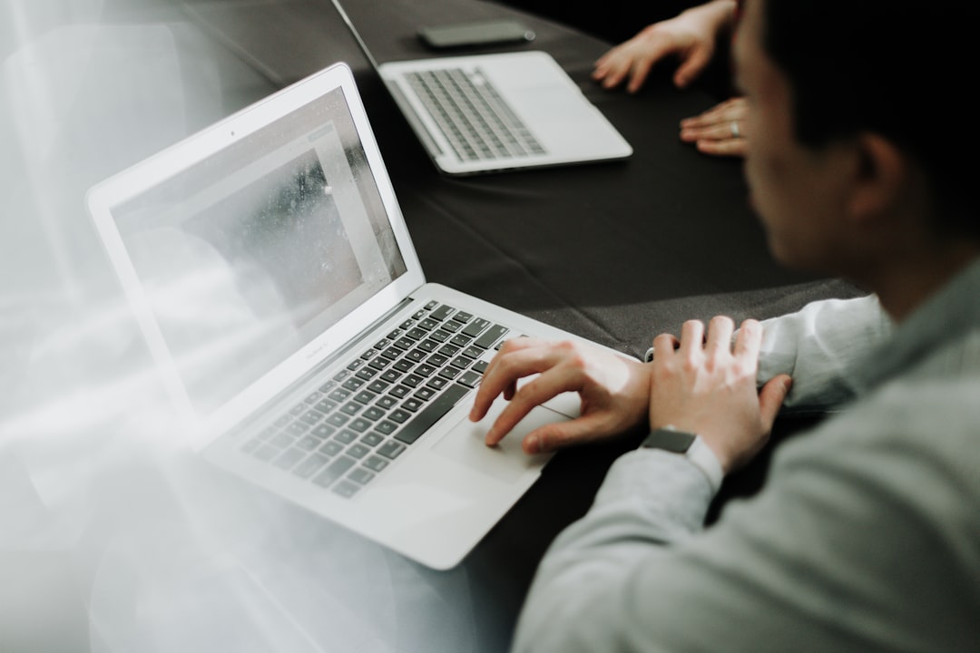 woman in orange long sleeve shirt sitting beside table with macbook pro
